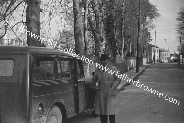 MAN AT SIDE OF CAR IN TOWN